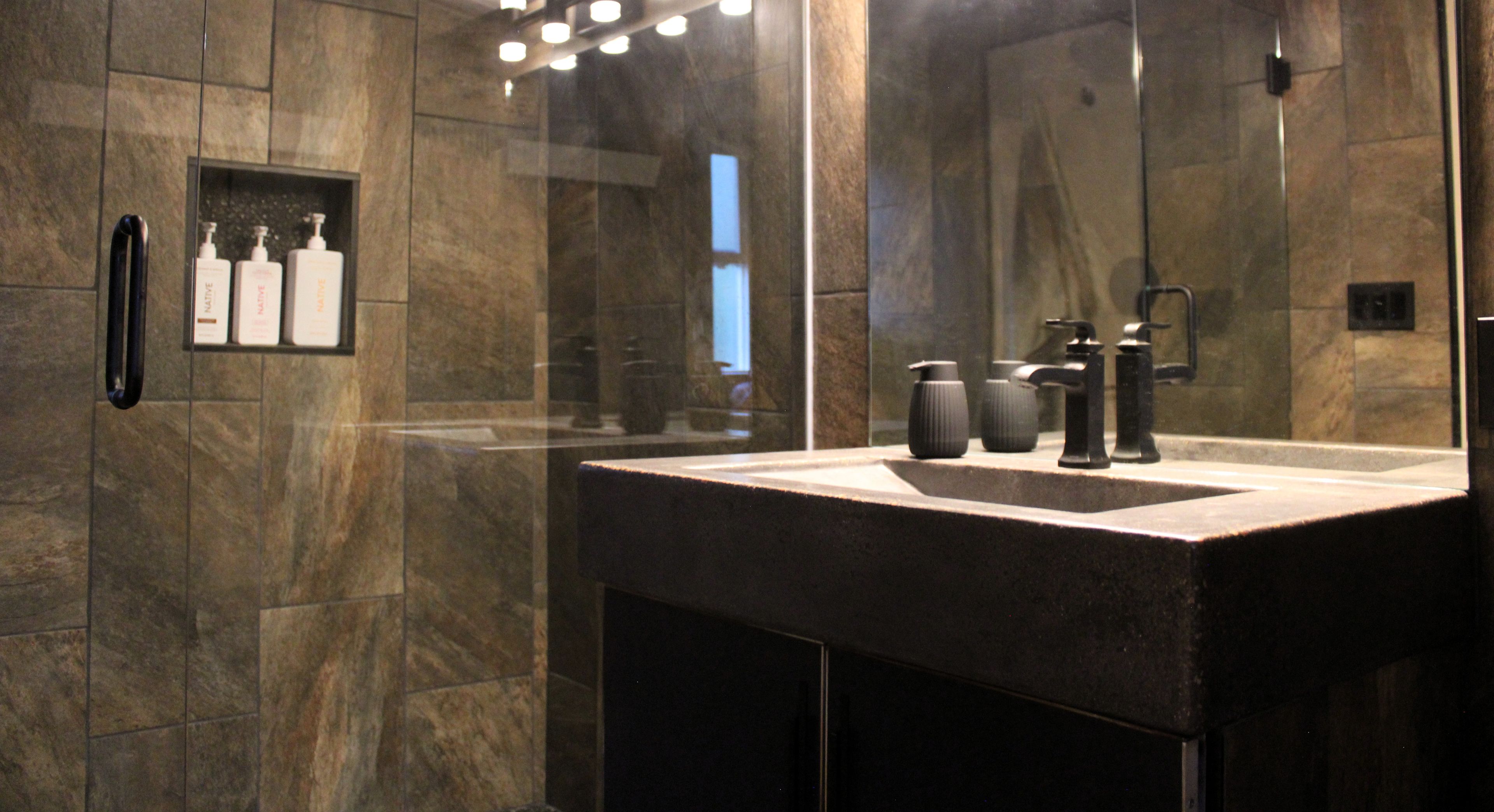 Un baño moderno con un espejo grande, un lavabo y una zona de ducha.