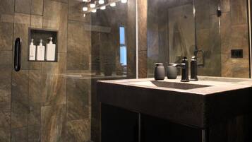 Un baño moderno con un espejo grande, un lavabo y una zona de ducha.