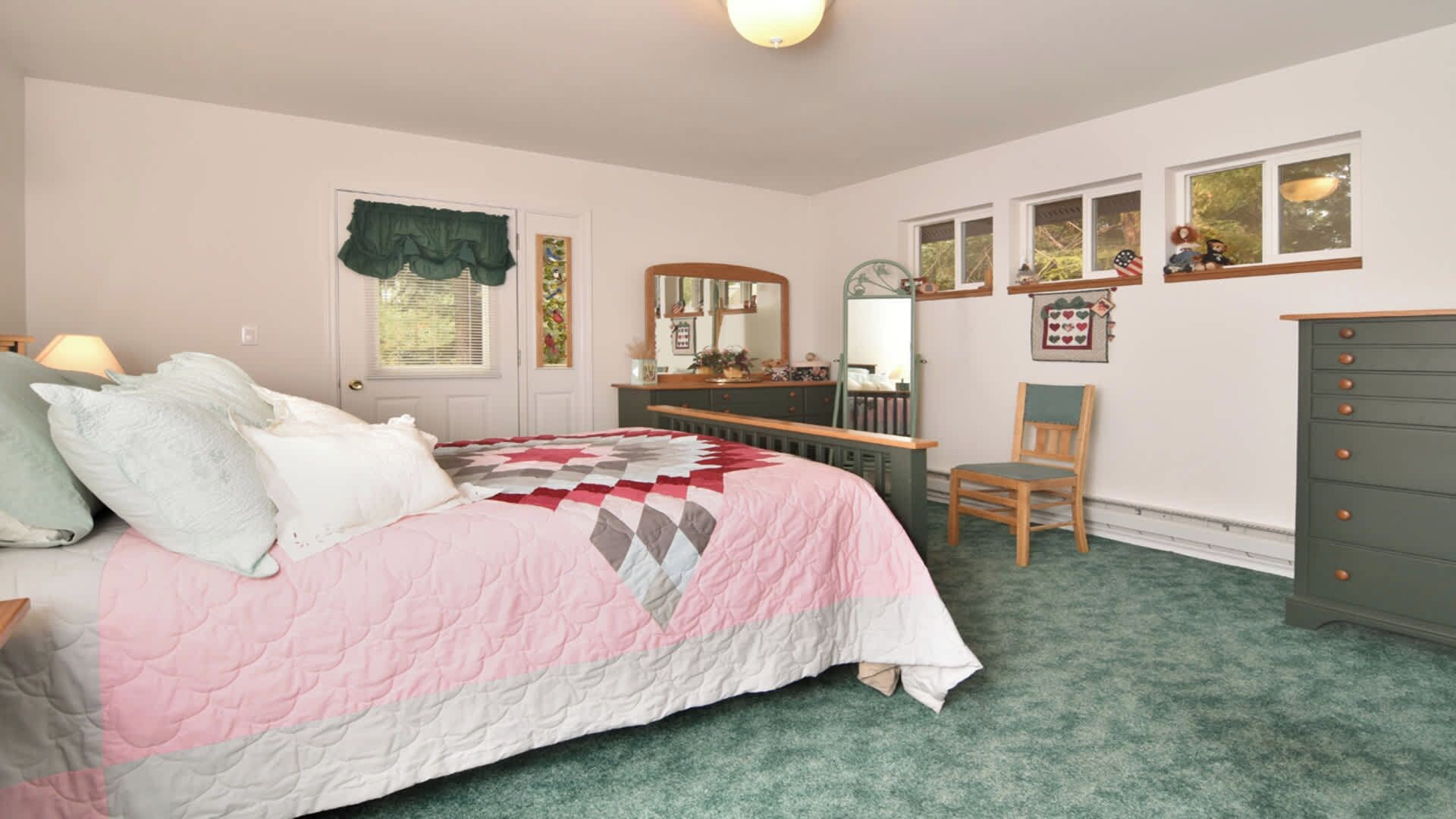 Un dormitorio con cama, cómoda, silla y aparador con cajones.