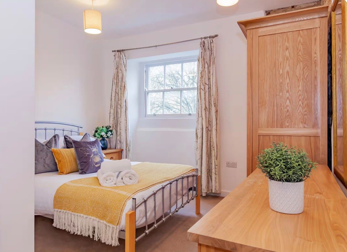 A bedroom with a bed, bedside table, and a window with curtains.
