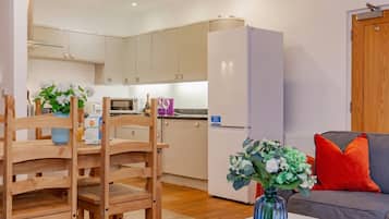 A modern kitchen with white cabinets, a refrigerator, and a dining area with wooden chairs and a table.