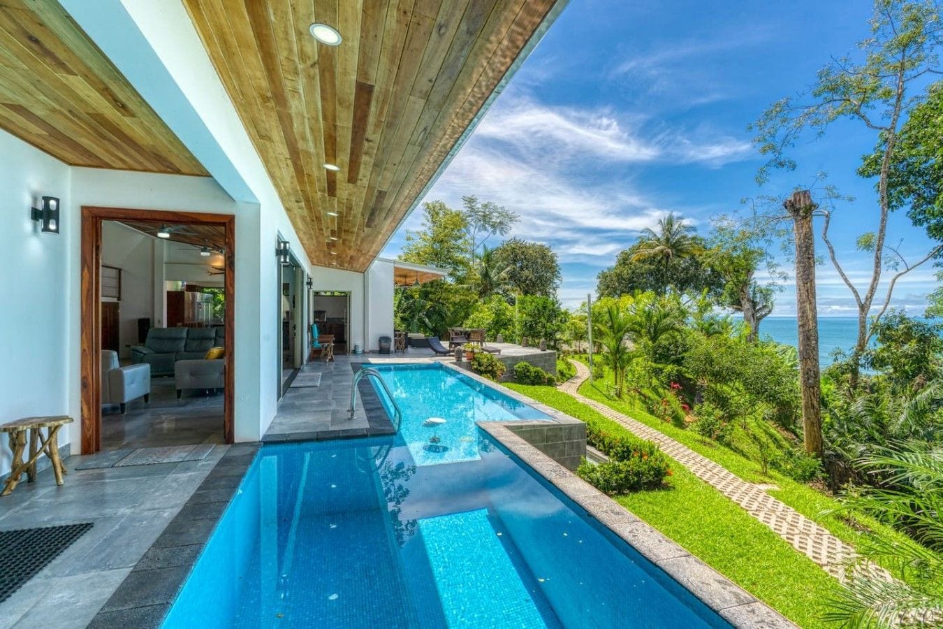 Une maison moderne dotée d’une piscine, d’un espace extérieur couvert et offrant une vue sur la mer.