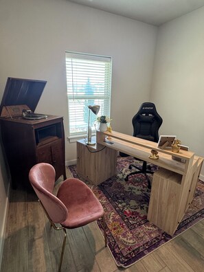 A room with a desk, a chair, a gaming chair, a vintage record player, a lamp, and a window with blinds. - 3-bedroom house in gorgeous Oklahoma City with AC (Oklahoma City)