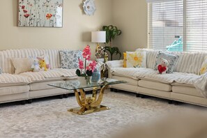 A living room with a sectional sofa, a glass coffee table with gold legs, and decorative pillows. - Vegas Luxe Retreat Pool, Pool Table, Near Strip (Las Vegas)