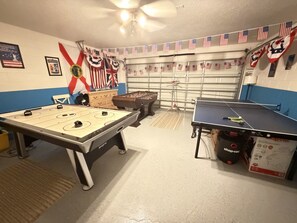 Une pièce équipée d’un baby-foot, d’une table de ping-pong et d’un billard. On y trouve des drapeaux américains et un drapeau mexicain.