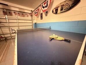 Une table de ping-pong dans une pièce aux murs bleus, décorée de drapeaux américains.