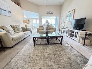 A living room with a sofa, coffee table, and TV. - The Sunset Retreat - Close to Disney World (Davenport)