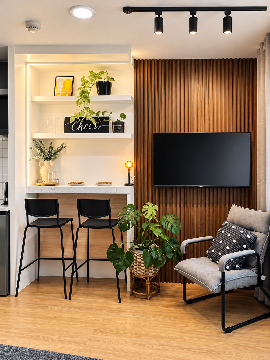 Un salon moderne doté d’un téléviseur à écran plat, d’un mur recouvert de panneaux en bois et d’un coin repas avec des tabourets de bar et une plante.