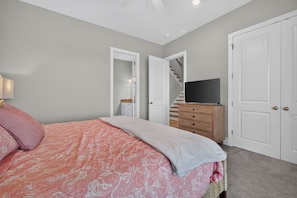 Quarto com cama, penteadeira, televisão e escada.