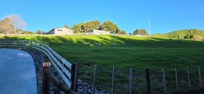 Paisatge rural amb una casa, un camp tancat per una tanca i un camí.