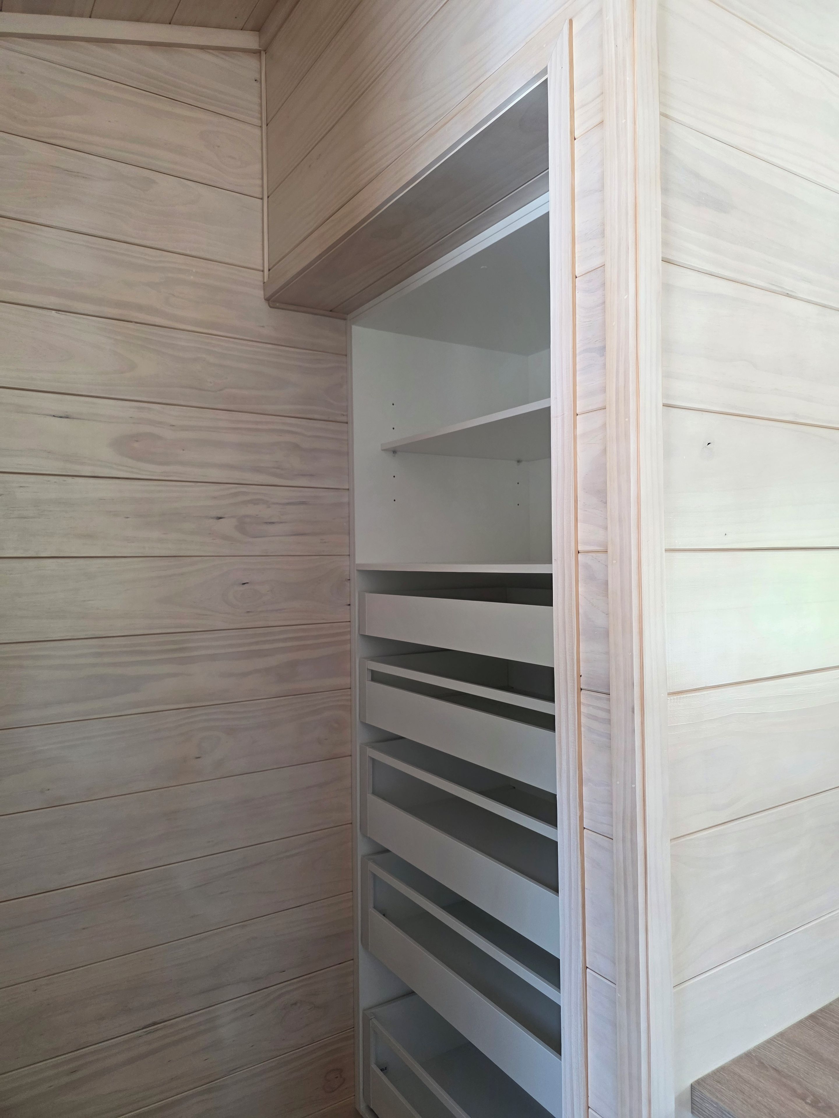A corner of a room with wooden paneling and a white built-in shelving unit.