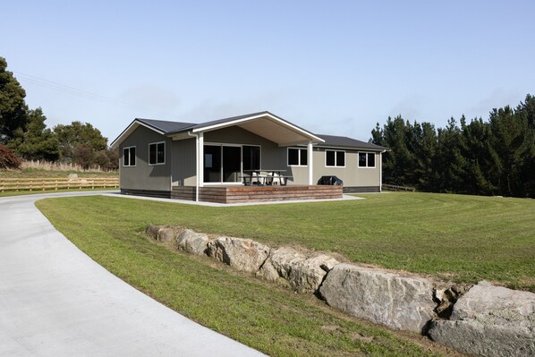 Une maison moderne à deux étages, dotée d’un patio couvert et d’une allée.
