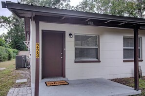 Ein Wohnhaus mit brauner Tür, Fußmatte und der Hausnummer 223 an der Wand.