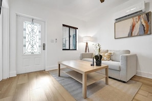 Una sala de estar con sofá, una mesa de centro, una lámpara y un cuadro en la pared.