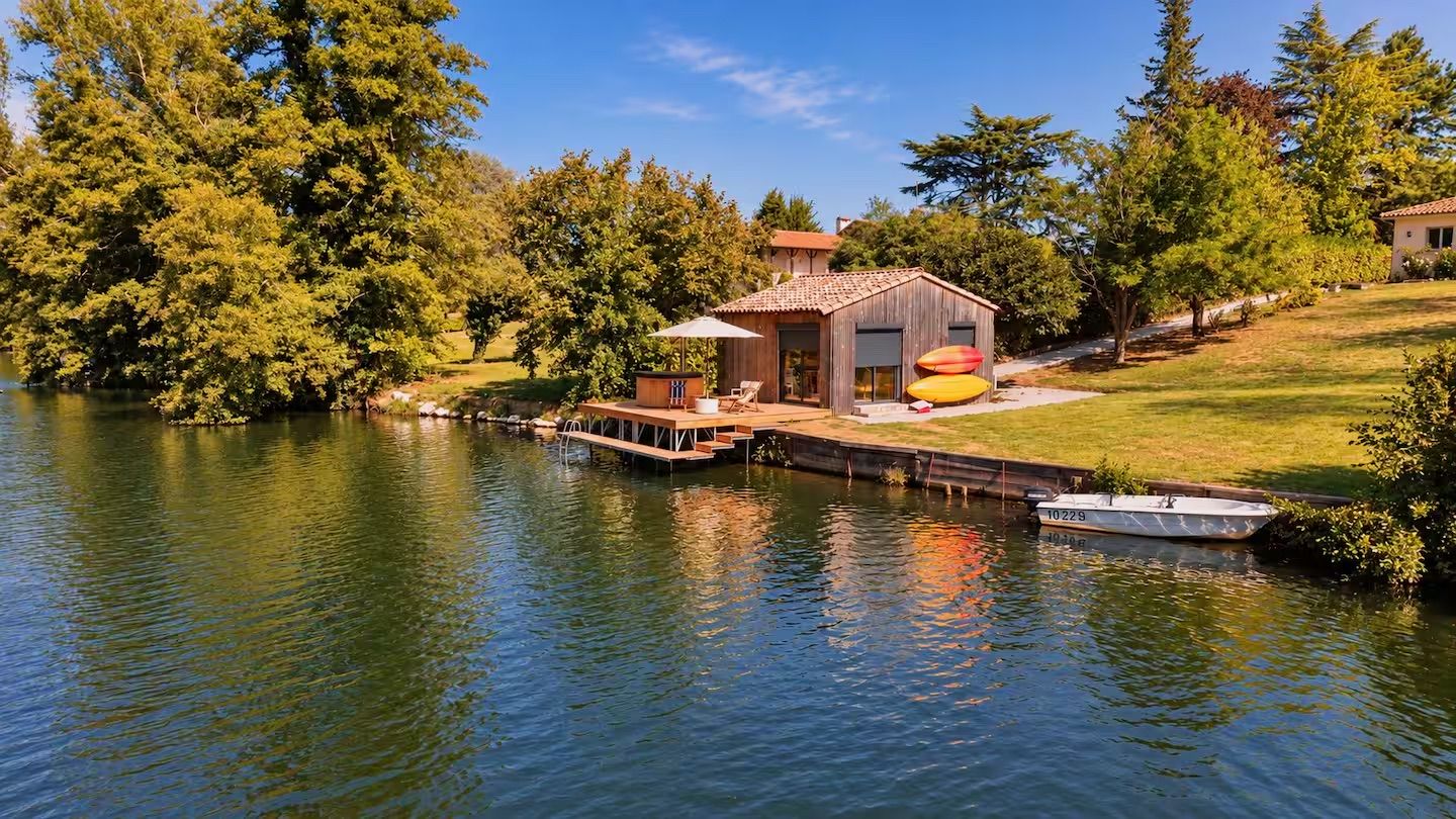 Una propietat a la vora d'un llac, amb un moll, un edifici petit i un vaixell.