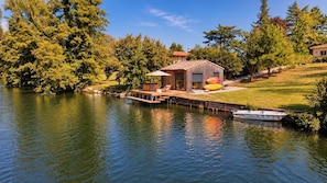 A lakeside property with a dock, a small building, and a boat.