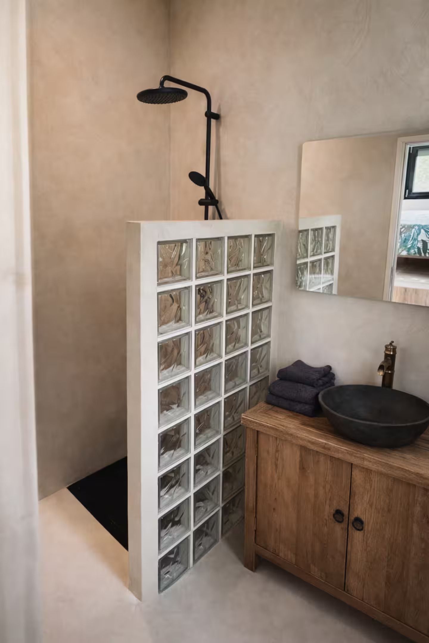 Een badkamer met een douche, wastafel en spiegel.