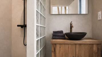 Une salle de bain avec un meuble-lavabo en bois, un lavabo noir et un miroir au-dessus.