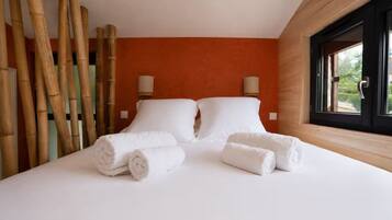 A hotel room with a bed, two pillows, two wall-mounted lamps, and a window with a view.