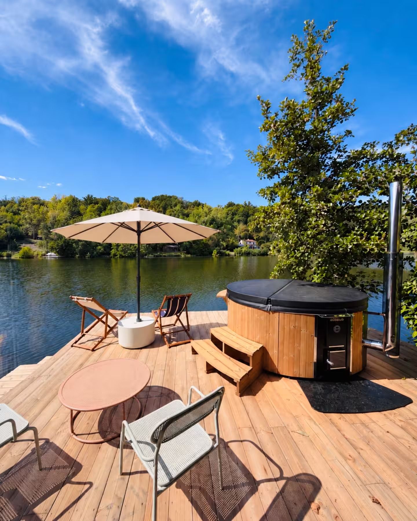 A wooden deck with outdoor furniture, a hot tub, and a view of a lake.