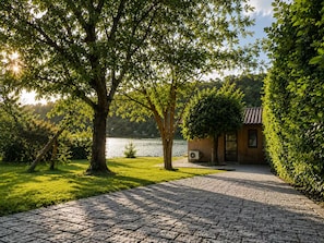 Un sendero pavimentado conduce a una cabaña de madera con vista al lago.