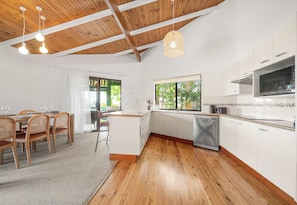 A modern kitchen with white cabinets, a stainless steel dishwasher, and a microwave. - The Breezy Abode - Dog-Friendly, Views & Deck (Caloundra Region)