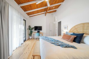 A bedroom with a wooden ceiling, a bed with pillows, a television on a stand, and a plant. - The Breezy Abode - Dog-Friendly, Views & Deck (Caloundra Region)