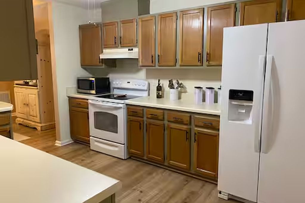 A kitchen with wooden cabinets, a white refrigerator, a microwave, and a stove.