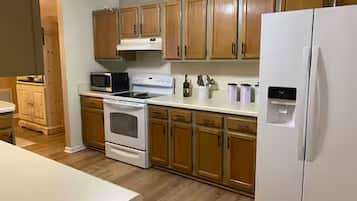 A kitchen with wooden cabinets, a white refrigerator, a microwave, and a stove.