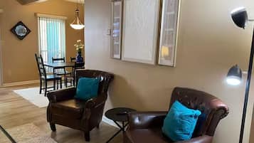 A living room with two leather armchairs, a dining table with chairs, and a floor lamp.