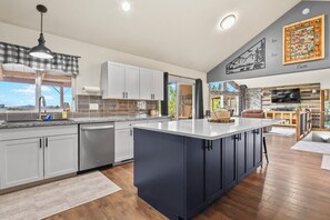 A modern kitchen with a large island, white cabinets, and a stone accent wall. - Quincy's Mountain Cabin Getaway with spectacular views and peaceful serenity! (Florissant)
