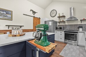 A modern kitchen with a central island, a mixer, a clock, and a stove. - Quincy's Mountain Cabin Getaway with spectacular views and peaceful serenity! (Florissant)