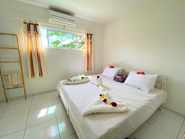 Une chambre d’hôtel avec un grand lit, une fenêtre avec des rideaux, une échelle en bois et un climatiseur fixé au mur.
