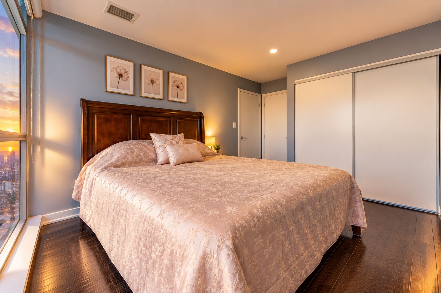 Un dormitorio con una cama grande, vistas de la ciudad a través de una ventana y un armario.