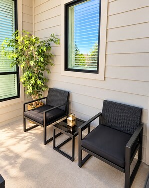 A patio area with two black chairs, a small table, and a potted plant. - The Napa Luxe Brand-New 2BR/2BA Sleeps 6. (Napa)