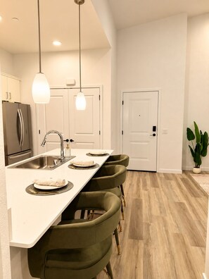 A modern kitchen with a central island, bar stools, a stainless steel sink, and pendant lighting. - The Napa Luxe Brand-New 2BR/2BA Sleeps 6. (Napa)