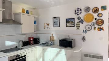A kitchen with white cabinets, a stove, a microwave, and a coffee maker.