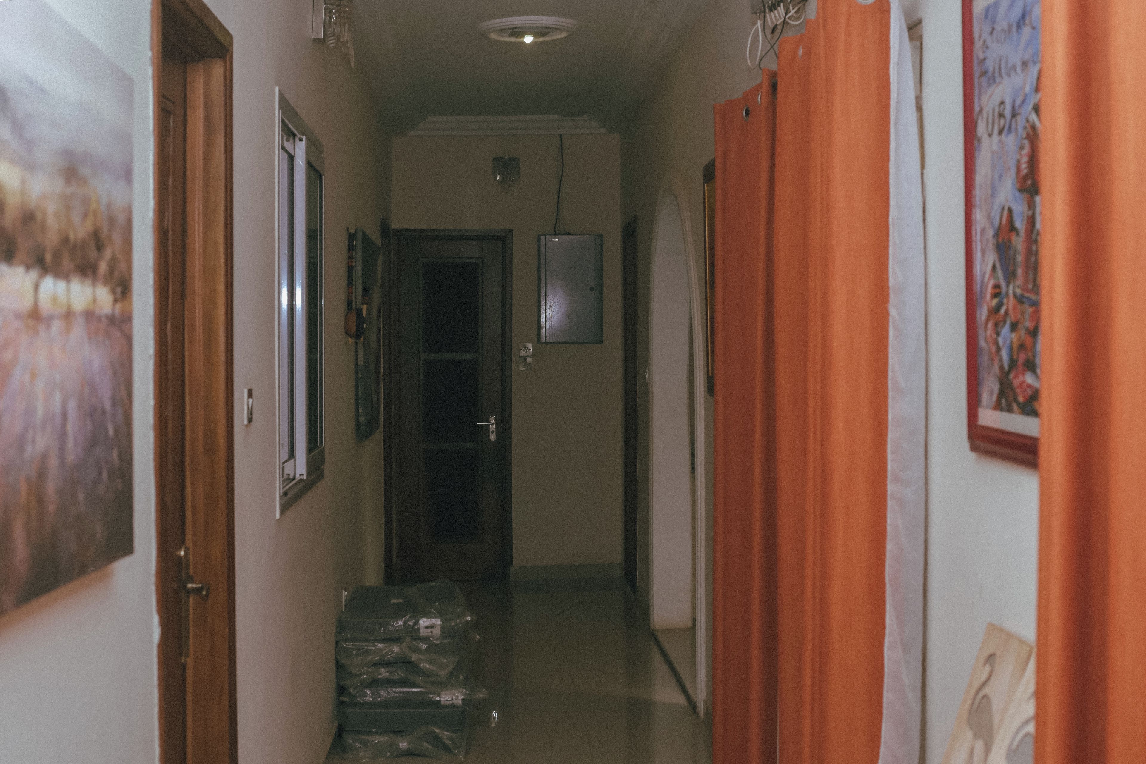 A narrow hallway with doors on both sides, a ceiling light, and a door at the end.