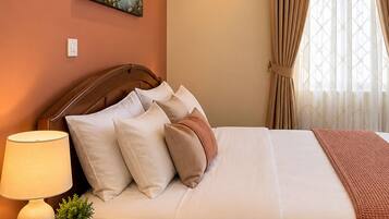 A neatly made bed with a wooden headboard, a bedside lamp, and a small potted plant.