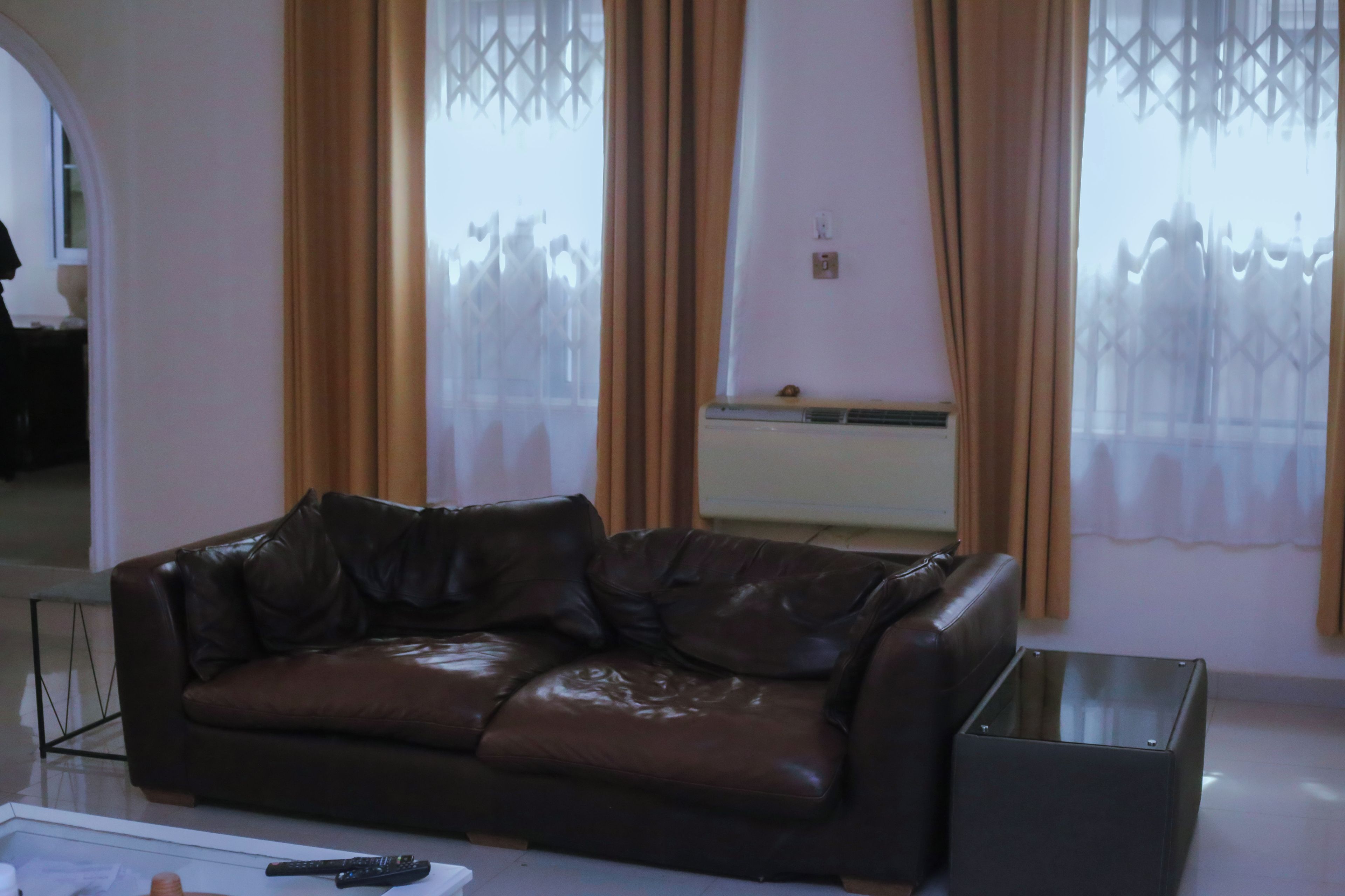 Una sala de estar con un sofá de cuero marrón, una mesita de centro y un mueble para televisión.