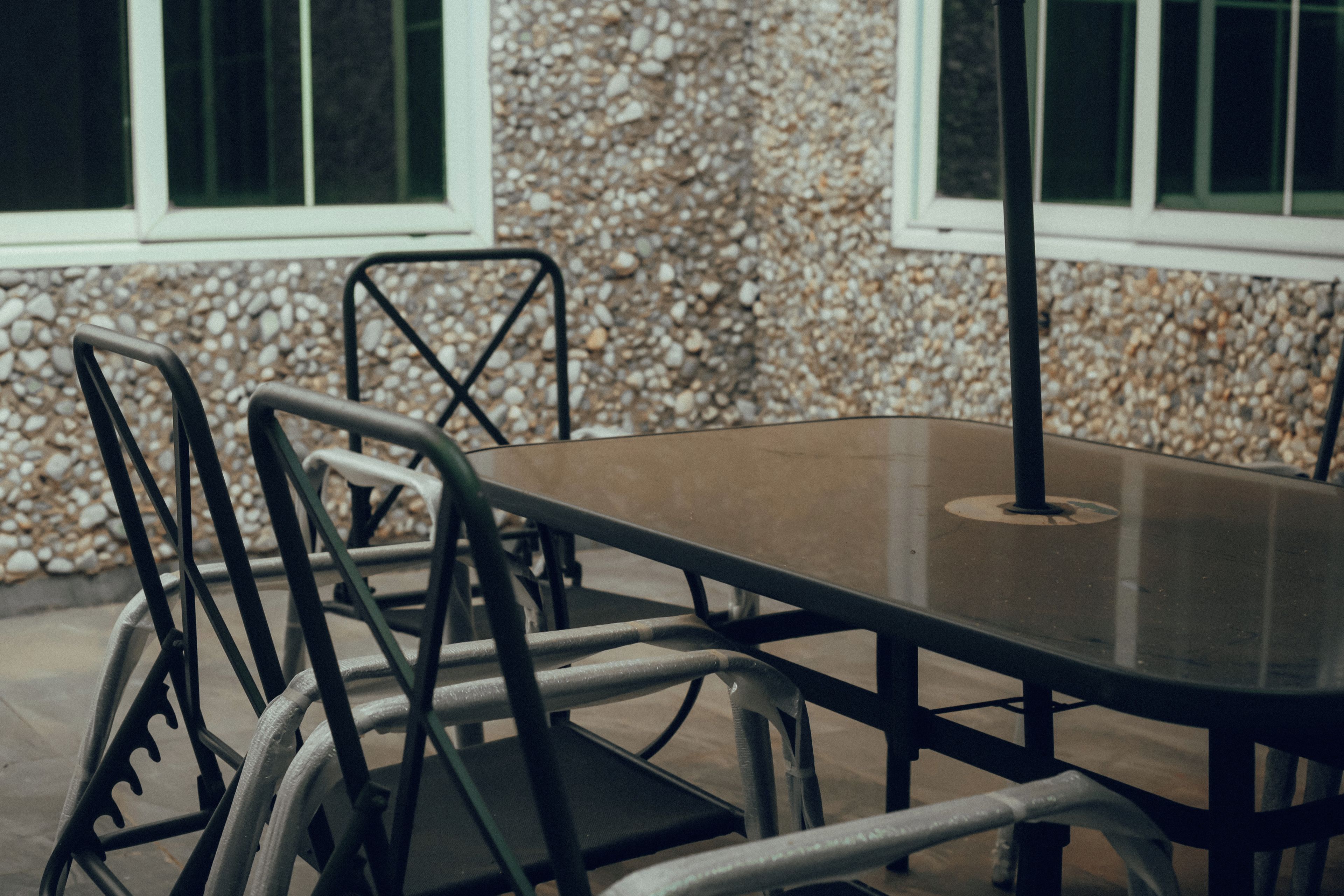 A dining table with chairs, a window, and a pebble wall.