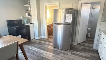 Una cocina con un refrigerador de acero inoxidable, un horno y una mesa de comedor.