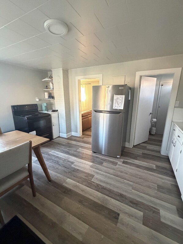 A kitchen with a stainless steel refrigerator, a stove, and a dining table.