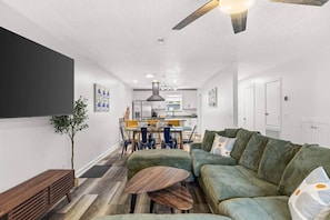 Ein modernes Wohnzimmer mit einem grünen Sofa, einem Holztisch und einem Essbereich mit Stühlen und einem Tisch.