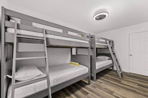 Quarto com beliche, escada, porta e luminária no teto.