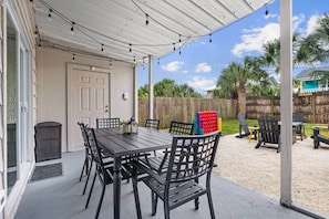 Dine beneath the covered patio and string lights, just outside the living room. The nearby electric BBQ includes an integrated temperature sensor, and a small charcoal grill offers another option. The fenced yard also has a fire pit and lawn games - The Yellow Retreat B | Beach Walk + Private Yard (Panama City Beach)