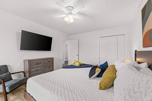A bedroom with a bed, a television, a ceiling fan, and a dresser. - The Yellow Retreat B | Beach Walk + Private Yard (Panama City Beach)