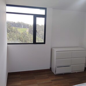 A room with a large window, a white dresser, and a view of a green landscape. - New Listing (Quito)