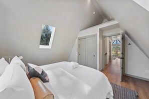 A bedroom with a bed, a nightstand, a window with a view, and a door leading to a balcony. - Stay Foxy - A Frame, Riverfront, Hot Tub, Fire Pit, Stunning Views! (Bend)