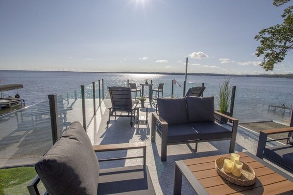 Une terrasse extérieure avec des sièges, une vue sur l’eau et un drapeau.
